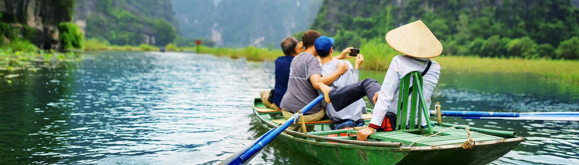 Zdjęcie przedstawiające trzech mężczyzn robiących sobie zdjęcia na łódce w azjatyckim kraju
